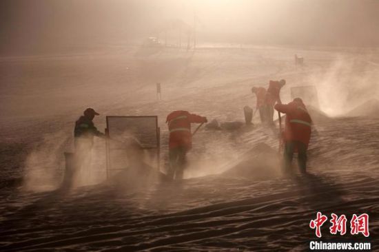 圖為敦煌市鳴沙山月牙泉景區(qū)“駱駝保姆”清理駱駝糞便?！垥粤?攝