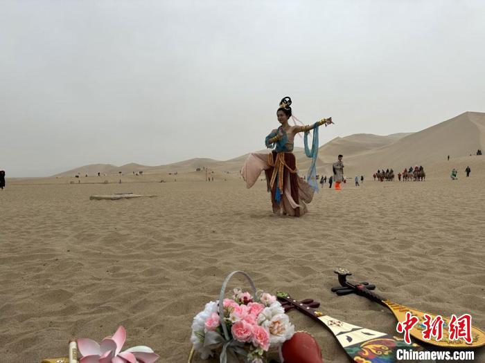 圖為2023年4月底，敦煌大漠“逐舞者”奧楠在鳴沙山月牙泉景區(qū)視頻直播敦煌舞?！●T志軍 攝