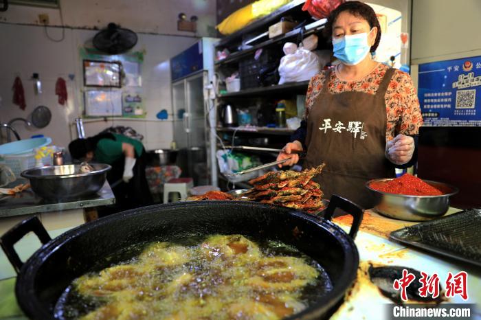 圖為平安驛·河湟民俗文化體驗地內(nèi)的商戶炸干板魚?！⊙Φ?攝